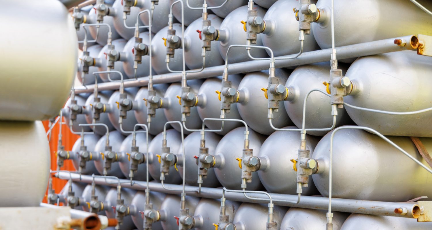 A lot of bottles filled with gas or gasoline are stacked in piles A lot of different small metal bottles filled with gas or gasoline are stacked in large piles and illuminated by the bright warm daytime sun
