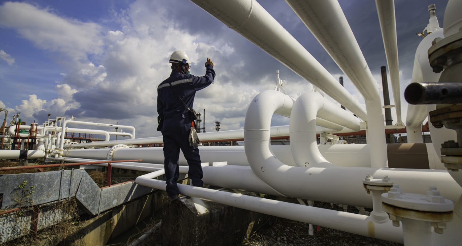 Male worker inspection at steel long pipes and pipe elbow in sta Male worker inspection at steel long pipes and pipe elbow in station oil factory during refinery valve of visual check record pipeline oil and gas industry.