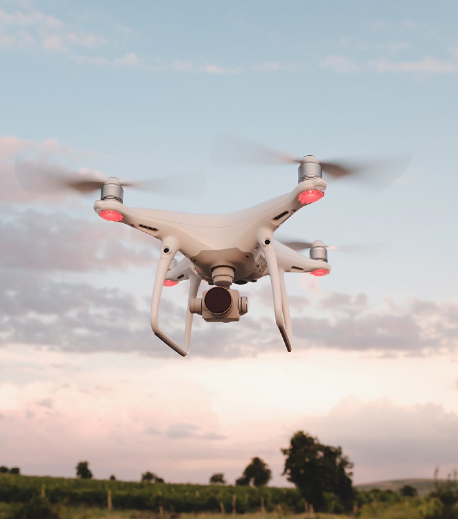 White drone hovering in a bright blue sky White drone hovering in a bright blue sky. Drone copter flying with digital camera